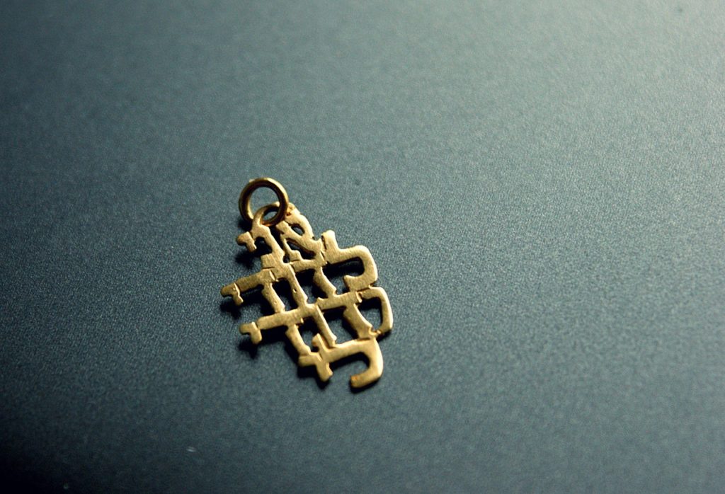 pendentif en or avec caractères hébreux sur fond gris