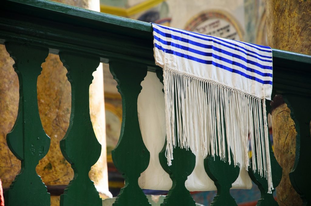 tallit bleu et blanc avec franges sur balustrade verte