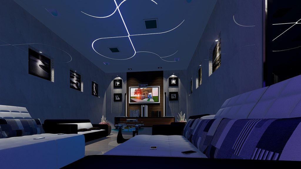 salle de cinéma maison moderne avec canapés bleus, écran central et néons au plafond