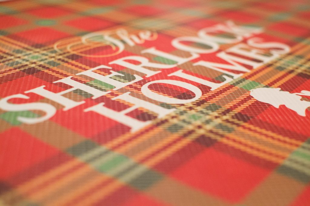 sherlock holmes écrit en lettres blanches sur tissu écossais rouge et tartan