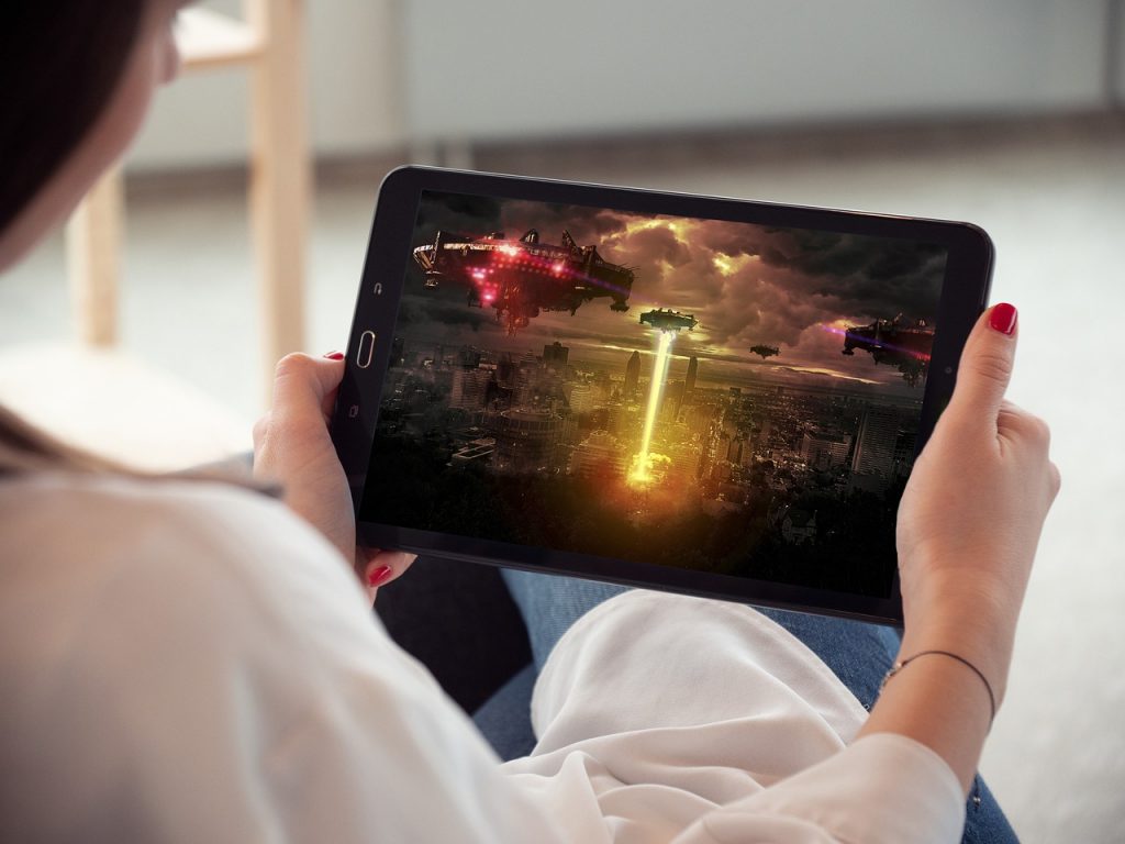 femme tenant une tablette affichant un jeu de science-fiction avec vaisseaux spatiaux