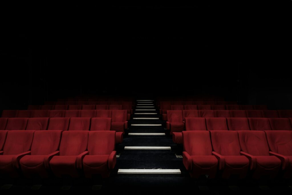 salle de cinéma vide avec rangées de fauteuils rouges et allée centrale