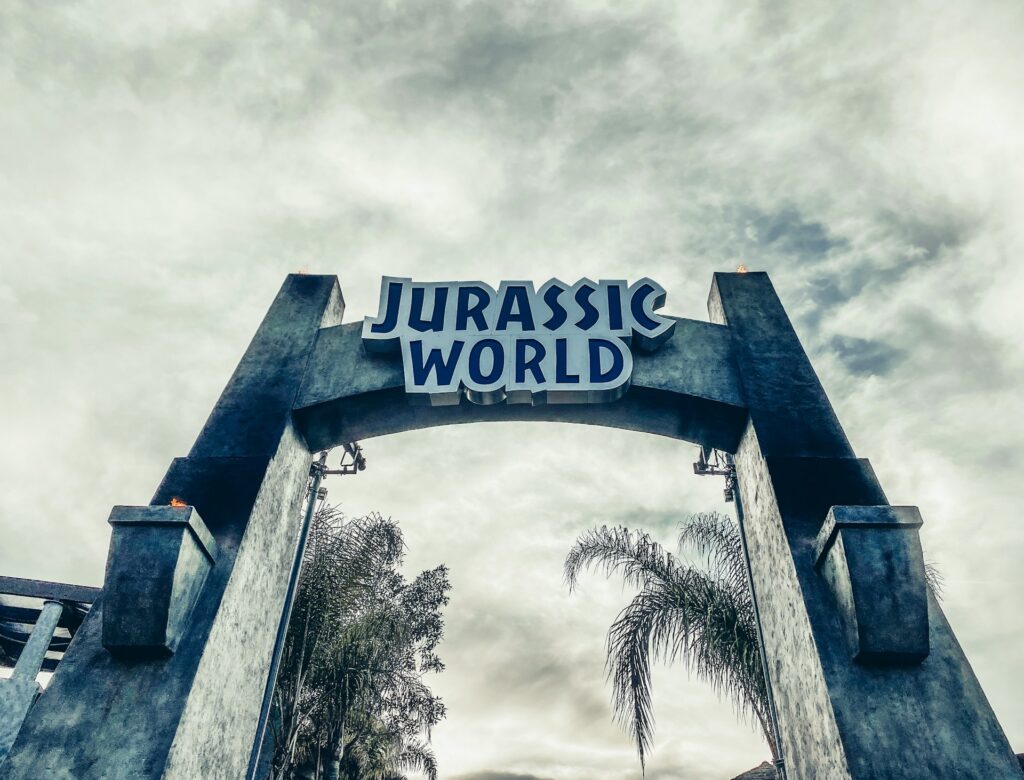 portail d'entrée jurassic world avec palmiers et ciel nuageux
