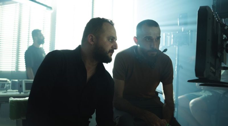 Film crew members collaborating in a Baghdad studio with dramatic lighting.