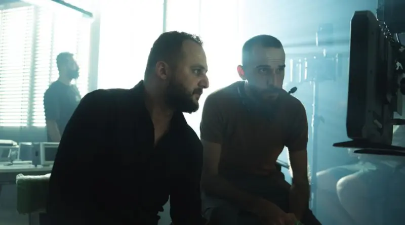 Film crew members collaborating in a Baghdad studio with dramatic lighting.