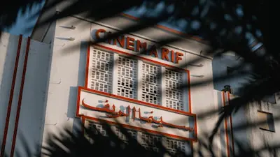 A vintage cinema is framed by palm leaves.