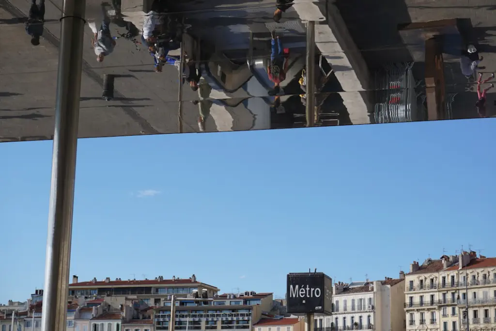 People reflected on a building facade against blue sky.