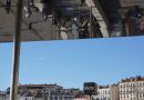 People reflected on a building facade against blue sky.