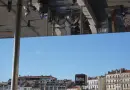 People reflected on a building facade against blue sky.