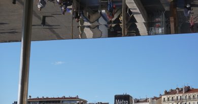 People reflected on a building facade against blue sky.