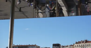 People reflected on a building facade against blue sky.