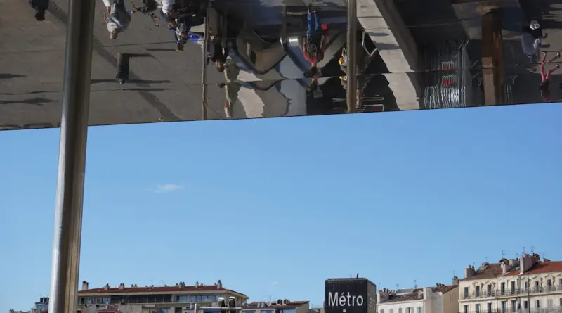 People reflected on a building facade against blue sky.