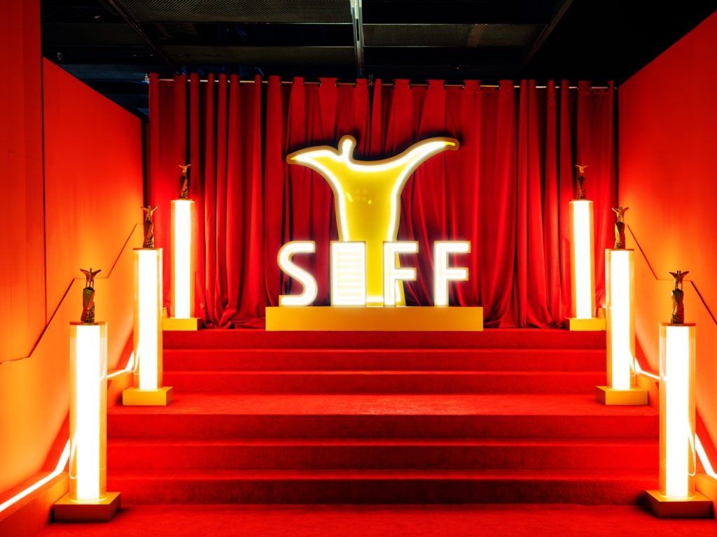 A red carpet entrance with siff logo and golden trophies.