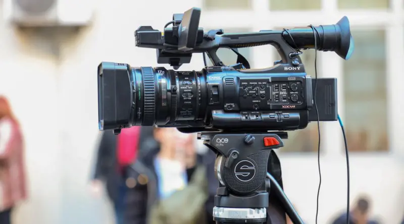 Close-up of a Sony video camera mounted on a tripod for outdoor filming.