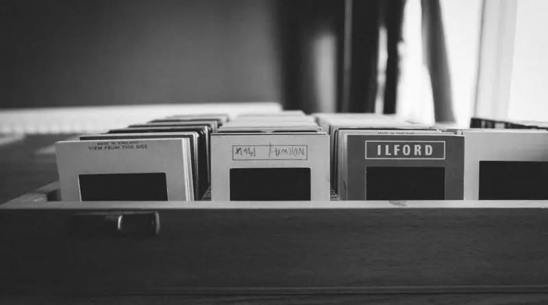 Black and white photo of vintage film slides organized in a wooden box.