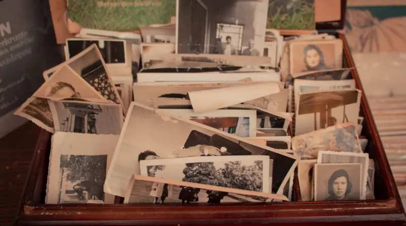 A collection of old black-and-white photographs stored in a vintage wooden box, evoking nostalgia.