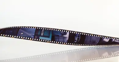 Cinéma juif algérien années 1960-1980 : réalisateurs oubliés Close-up of a vintage film strip on a white reflective background, conveying nostalgia.