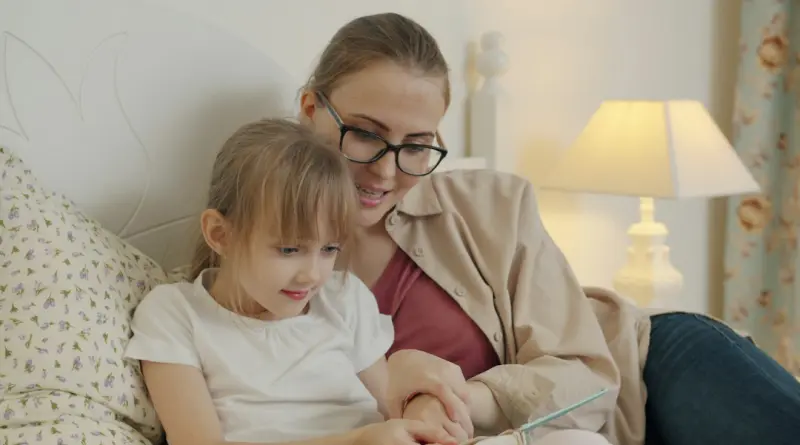 Mother and daughter reading a book in bed